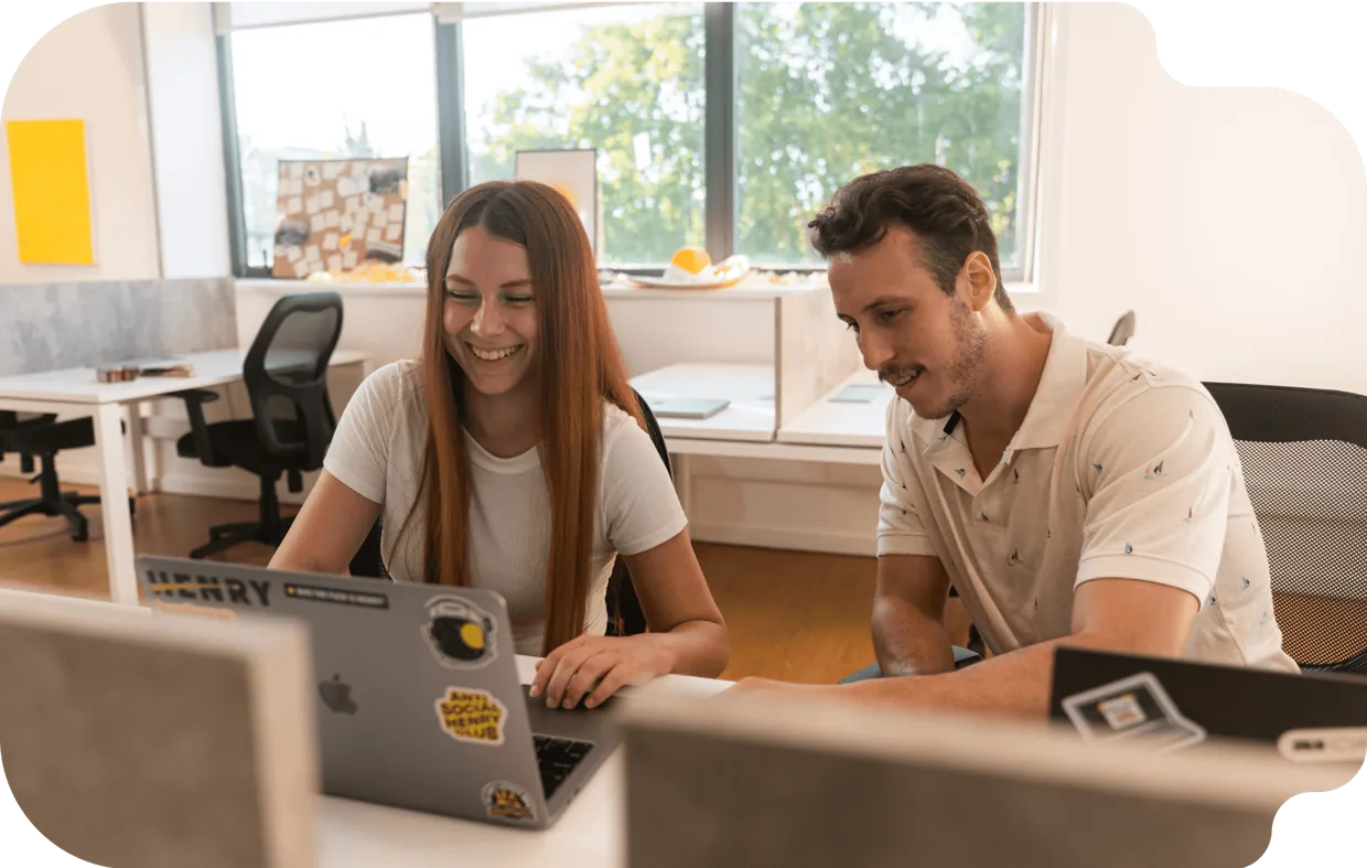 Two Henry graduates working together on a laptop in an office