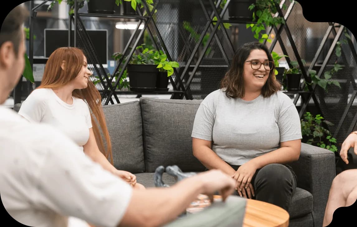 Henry graduates talking on a couch in a coworking space